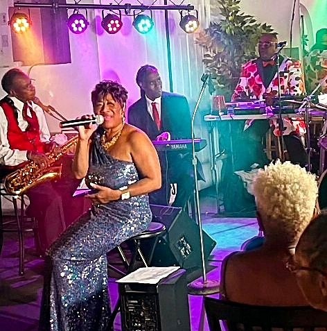 Trané N'Chel performing seated in a sequined gown